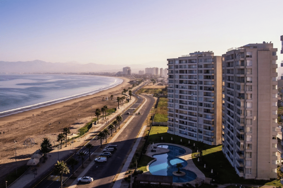 High-angle view of a beachfront avenue with high-rise apartment buildings and a pool at sunset.
